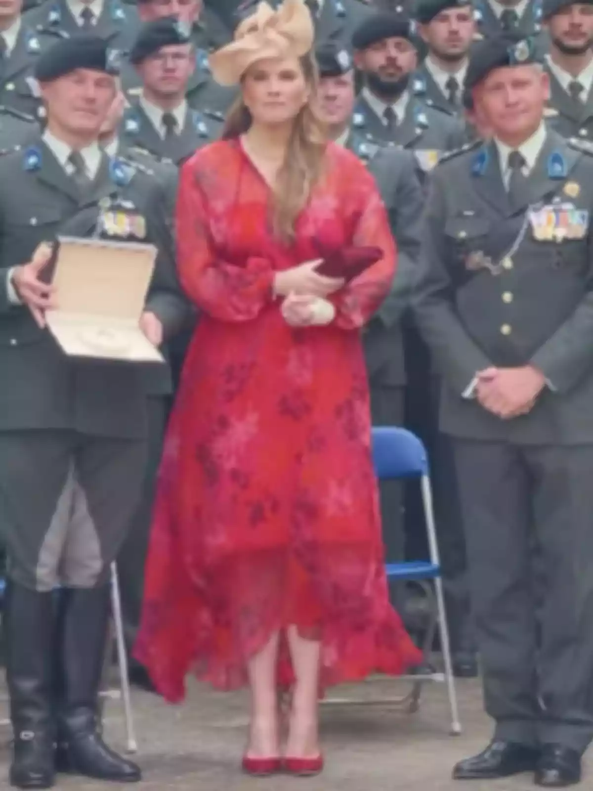 Woman in a red dress and elegant hat posing with two uniformed men at an official event Woman in a red dress and elegant hat posing with two uniformed men at an official event