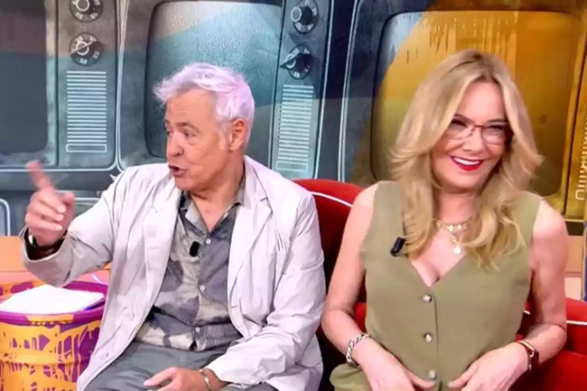 Dues persones assegudes en un plató de televisió, una d’elles gesticulant amb la mà mentre l’altra somriu, amb pantalles antigues de fons. Dues persones assegudes en un plató de televisió, una d’elles gesticulant amb la mà mentre l’altra somriu, amb pantalles antigues de fons.