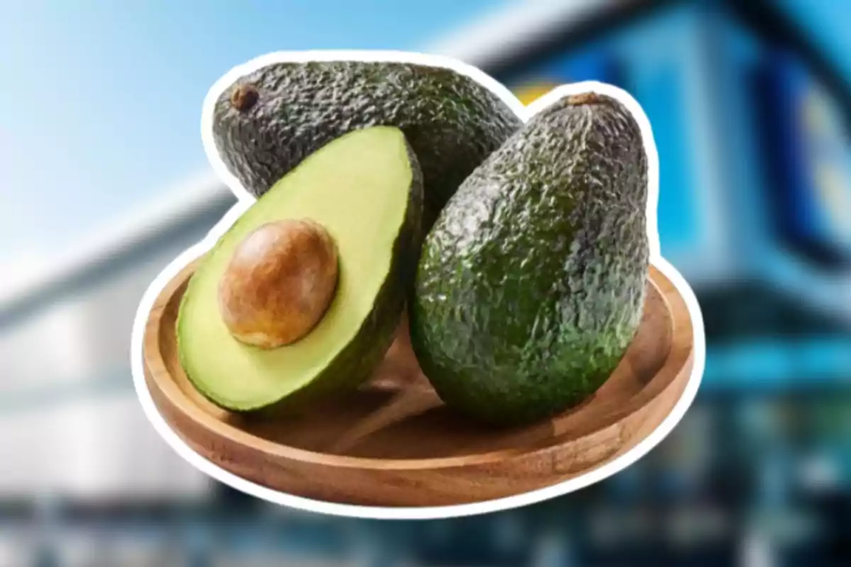 Tres aguacates sobre un plato de madera uno de ellos partido a la mitad mostrando la semilla Tres aguacates sobre un plato de madera uno de ellos partido a la mitad mostrando la semilla