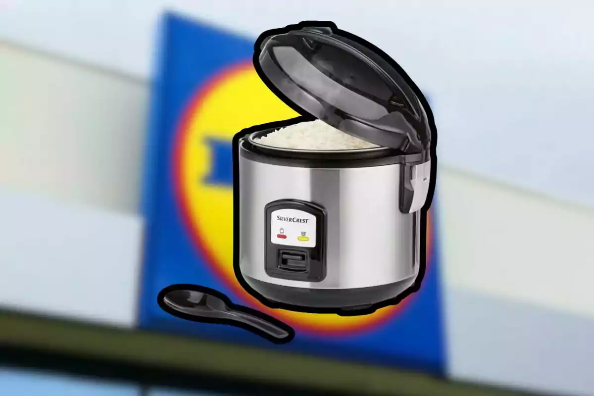 Stainless steel electric rice cooker with open lid and cooked rice in front of a blurry supermarket sign Stainless steel electric rice cooker with open lid and cooked rice in front of a blurry supermarket sign