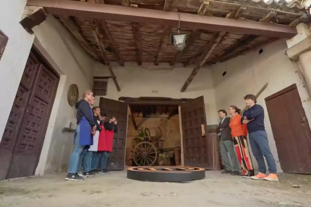 Un grup de persones dividit en dos equips es troba en un pati rústic davant de tres jutges, amb un carro antic al fons i un sostre de fusta vista a 'MasterChef'. Un grup de persones dividit en dos equips es troba en un pati rústic davant de tres jutges, amb un carro antic al fons i un sostre de fusta vista a 'MasterChef'.