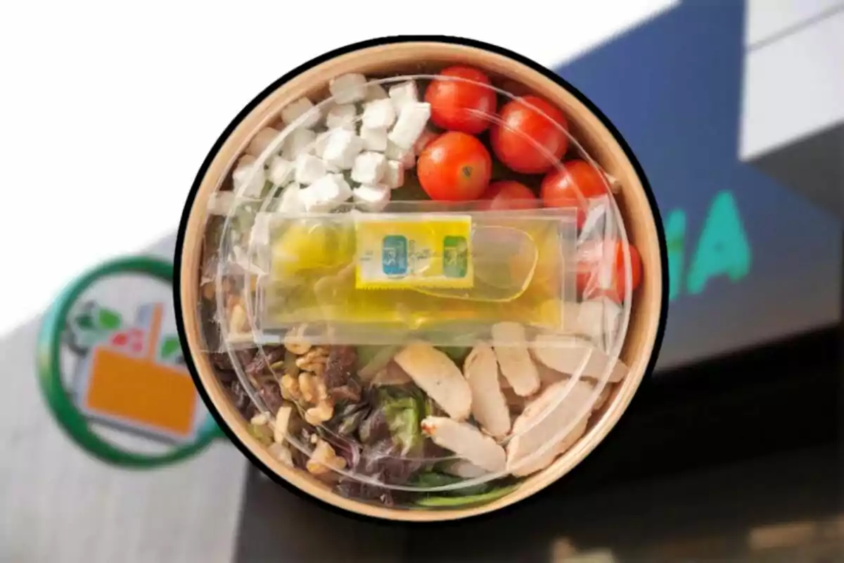 Salad in a cardboard container with chicken, cherry tomatoes, cheese, nuts, and packaged dressing, seen from above in front of a store Salad in a cardboard container with chicken, cherry tomatoes, cheese, nuts, and packaged dressing, seen from above in front of a store