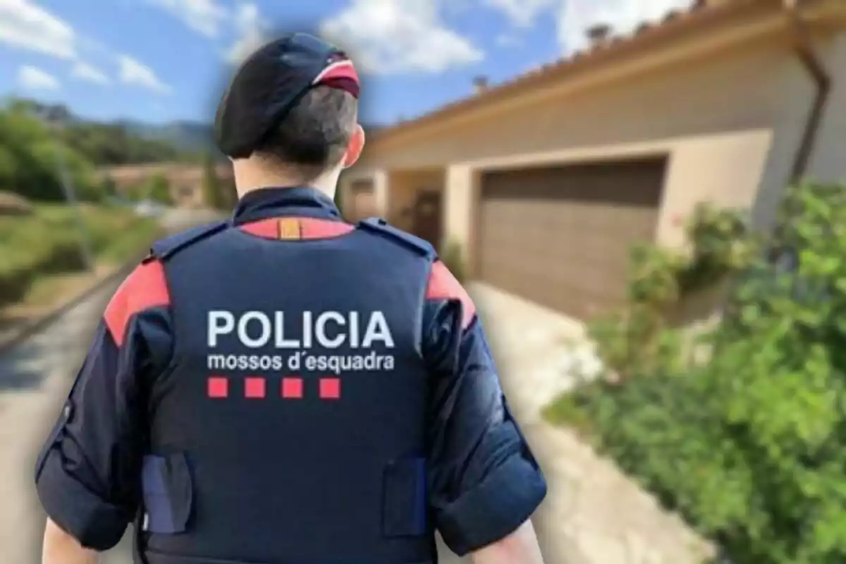 Agent dels Mossos d'Esquadra d'esquena davant d'una casa en una zona residencial
