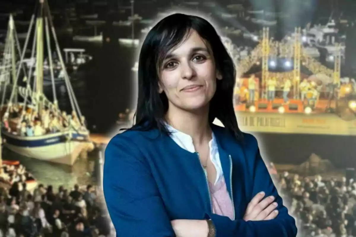 Dona de cabell fosc i jaqueta blava posant amb els braços creuats davant d’un fons d’un esdeveniment nocturn amb vaixells i un escenari il·luminat