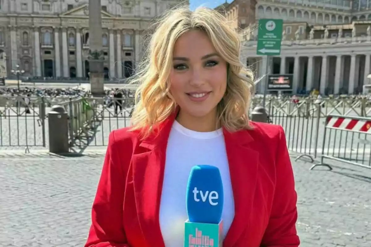 Marta Riesco rossa amb jaqueta vermella sosté un micròfon blau de tve de 'La família de la tele'