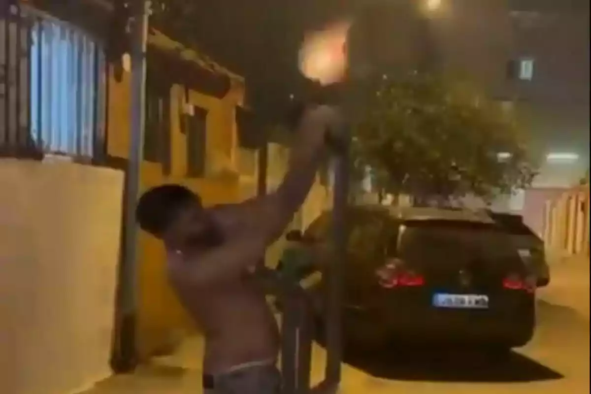 Home sense camisa disparant una arma llarga cap al cel en un carrer de nit