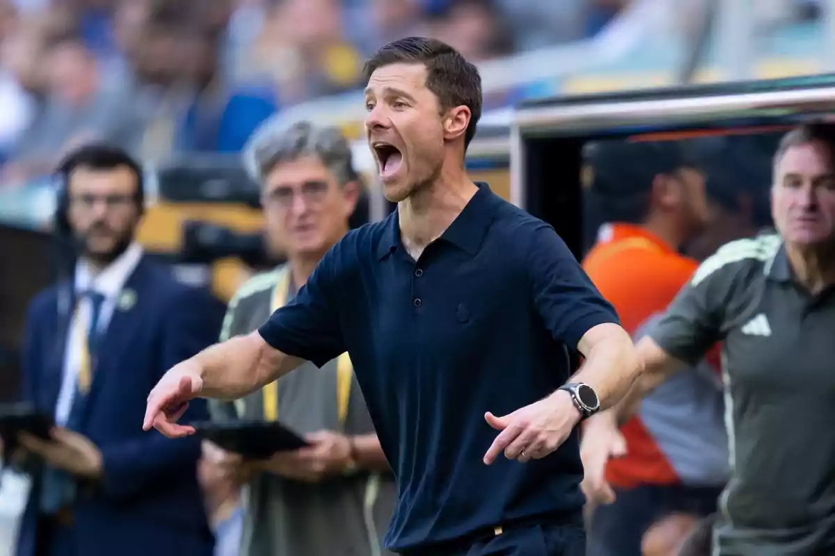 Soccer coach giving instructions on the sideline during a match with an intense expression and people in the background watching Soccer coach giving instructions on the sideline during a match with an intense expression and people in the background watching