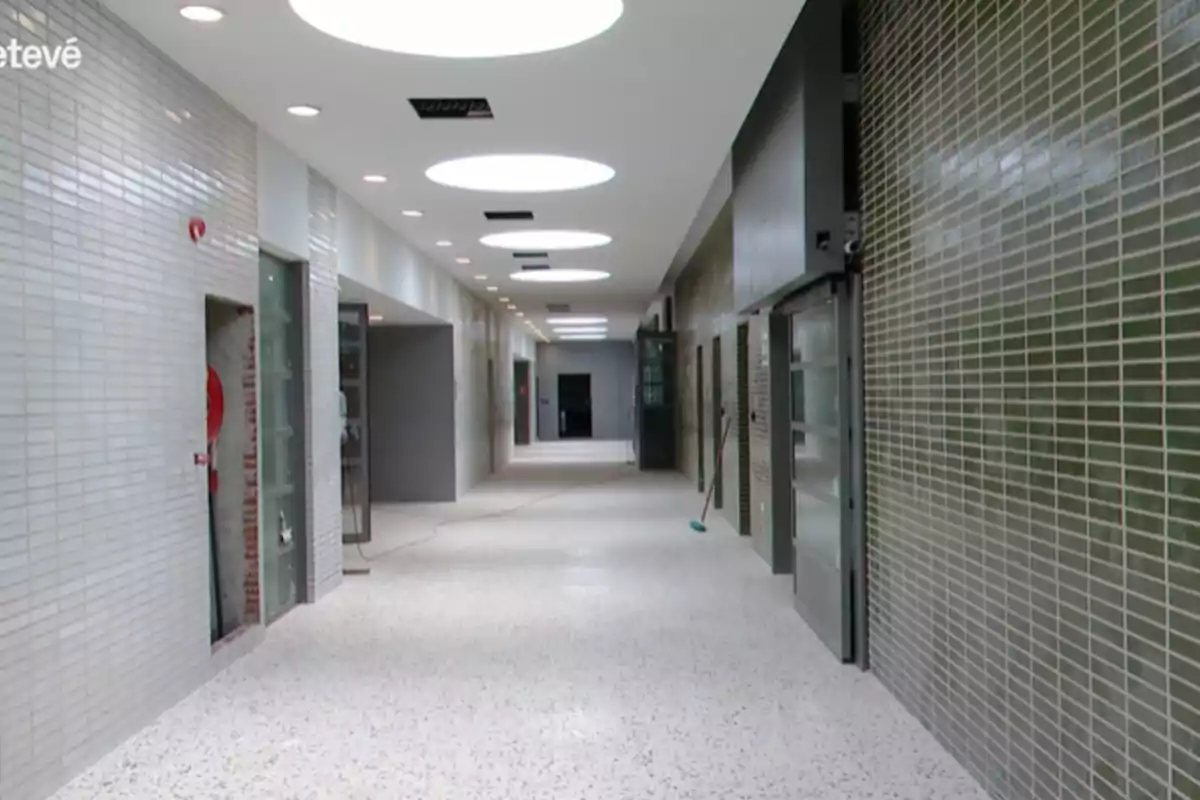 Pasillo interior de un edificio moderno con paredes de azulejos y techo blanco con luces circulares Pasillo interior de un edificio moderno con paredes de azulejos y techo blanco con luces circulares