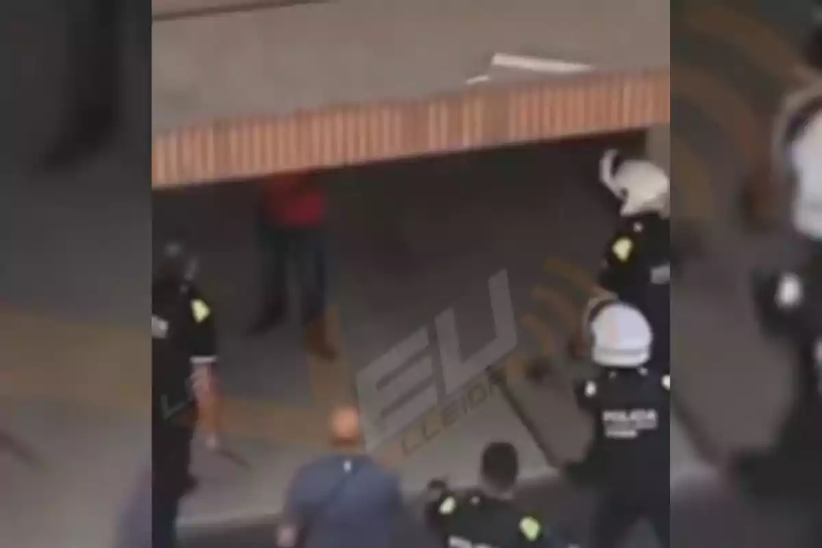 Diversos policies envolten una persona que es troba parcialment oculta darrere d’una cortina metàl·lica mig oberta.