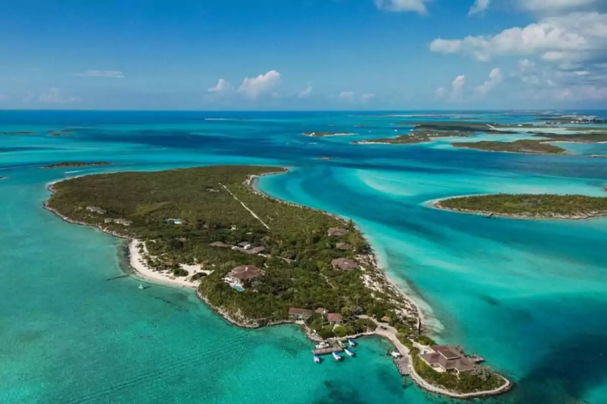 Vista aérea de una isla tropical rodeada de aguas turquesa y pequeñas embarcaciones junto a la costa Vista aérea de una isla tropical rodeada de aguas turquesa y pequeñas embarcaciones junto a la costa