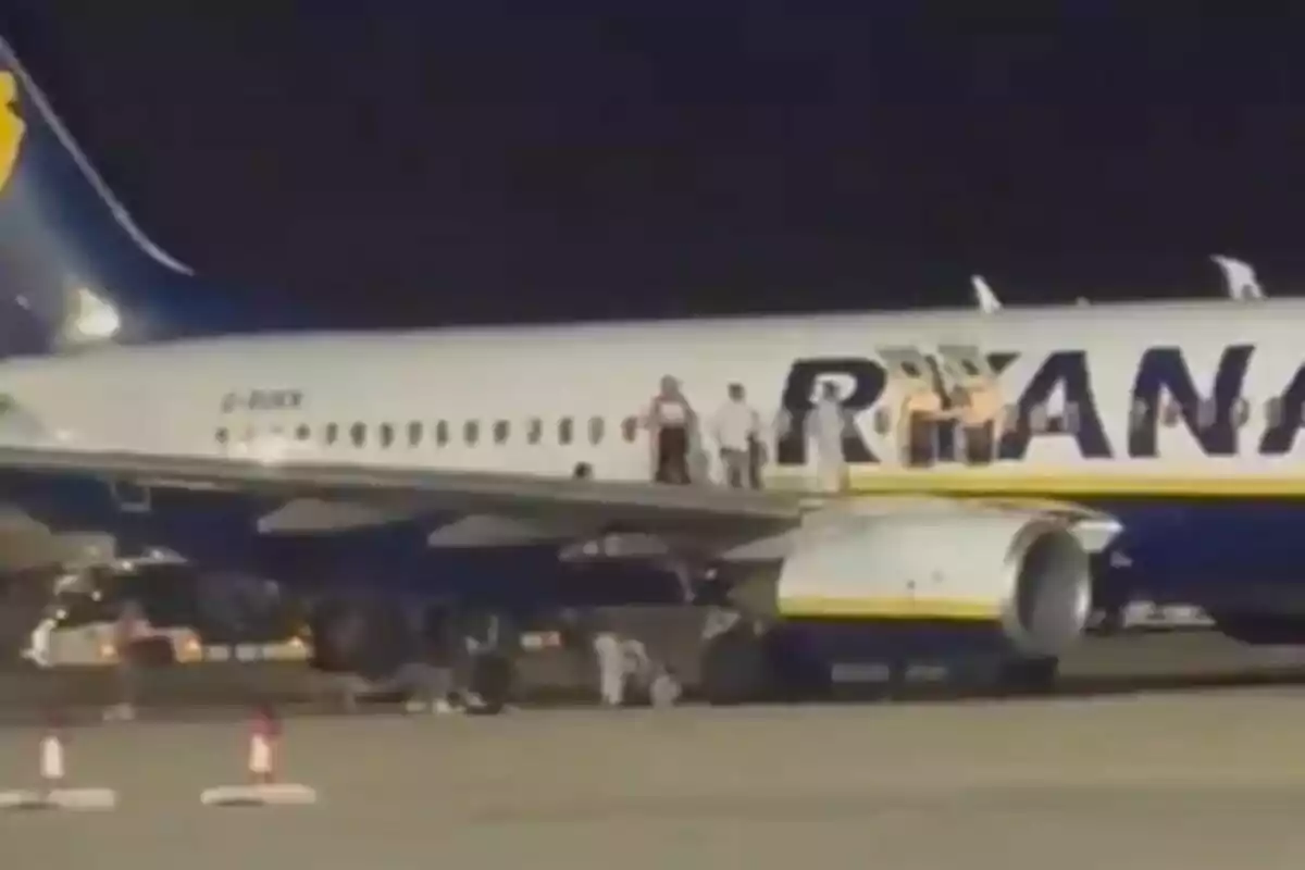 Persones dretes sobre l’ala d’un avió de Ryanair a la pista durant la nit. Persones dretes sobre l’ala d’un avió de Ryanair a la pista durant la nit.