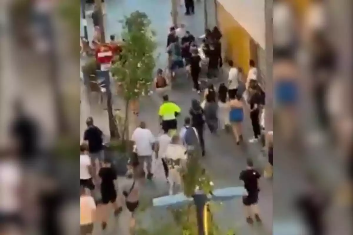 Diverses persones corren per un carrer de vianants en el que sembla ser una situació de caos o emergència.