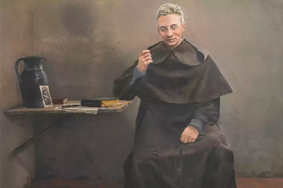 Un fraile de cabello canoso y gafas está sentado en una celda sencilla, vestido con un hábito marrón, sosteniendo un rosario en la mano derecha y con una expresión serena, a su lado hay una mesa de piedra con libros, una jarra y una fotografía. Un fraile de cabello canoso y gafas está sentado en una celda sencilla, vestido con un hábito marrón, sosteniendo un rosario en la mano derecha y con una expresión serena, a su lado hay una mesa de piedra con libros, una jarra y una fotografía.