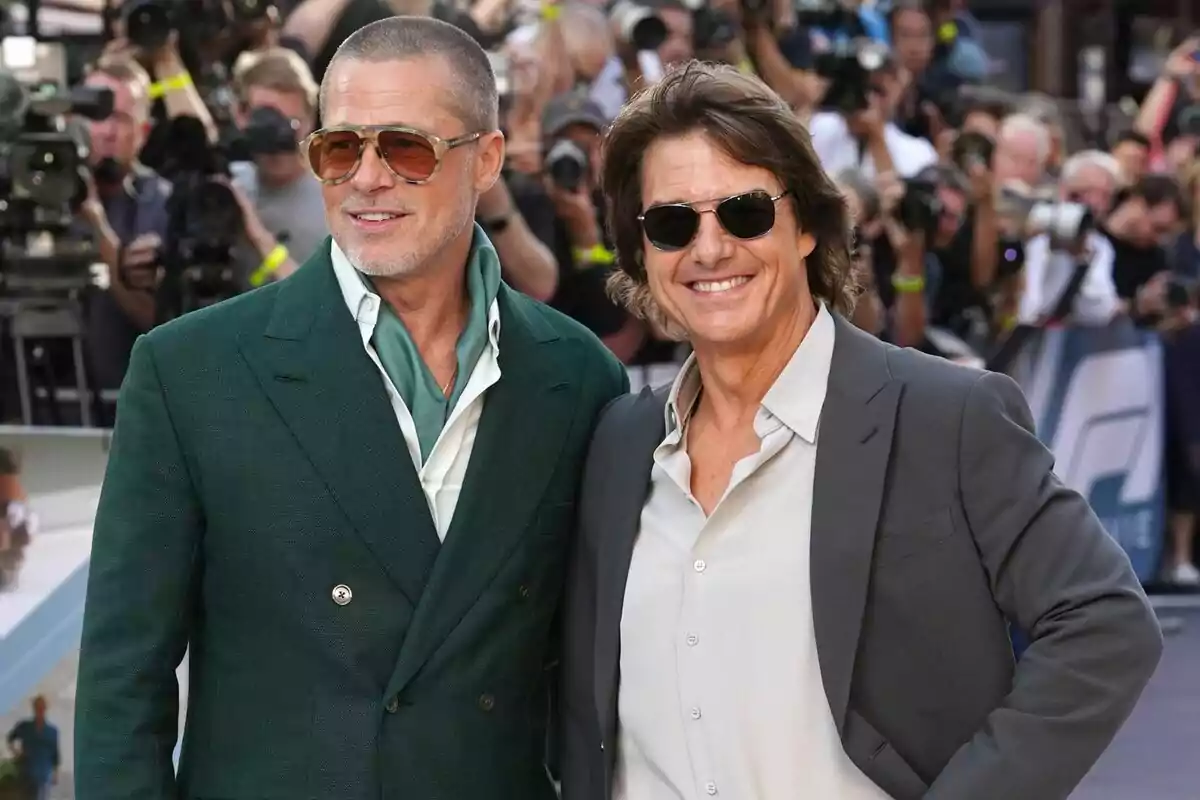 Dos homes amb ulleres de sol i vestits elegants, que són Brad Pitt i Tom Cruise, posen somrients en una catifa vermella envoltats de fotògrafs i públic. Dos homes amb ulleres de sol i vestits elegants, que són Brad Pitt i Tom Cruise, posen somrients en una catifa vermella envoltats de fotògrafs i públic.