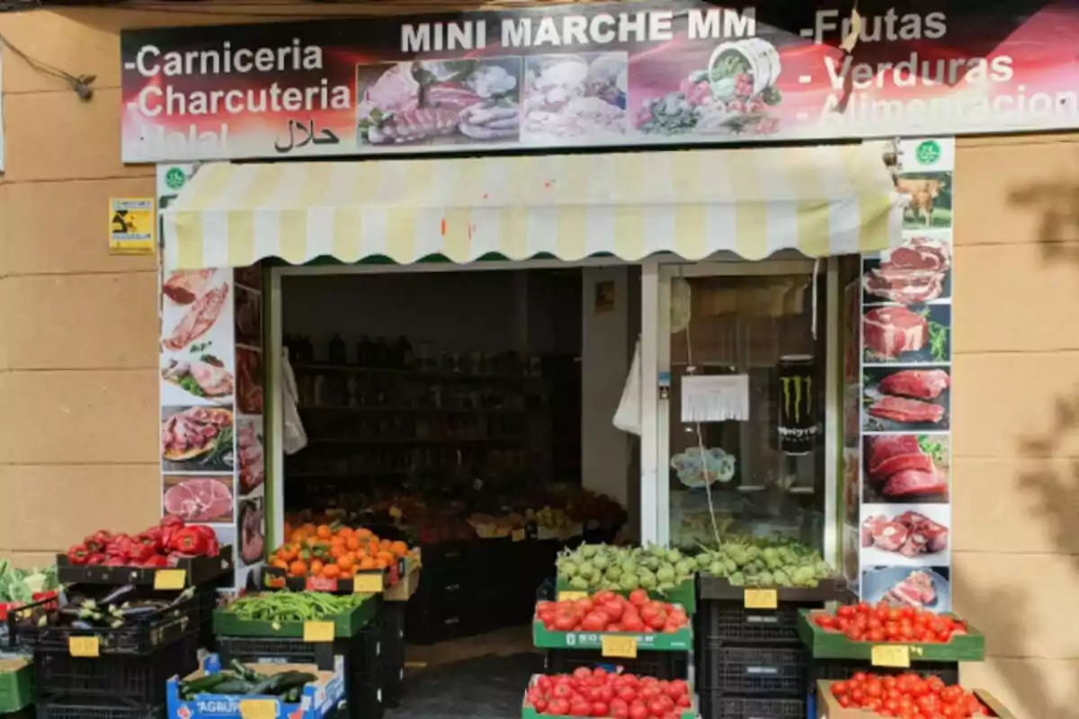 Botiga de barri amb fruita i verdura fresca exposada en caixes davant de l’entrada i cartells de carnisseria halal i xarcuteria al rètol superior, situada a França. Botiga de barri amb fruita i verdura fresca exposada en caixes davant de l’entrada i cartells de carnisseria halal i xarcuteria al rètol superior, situada a França.