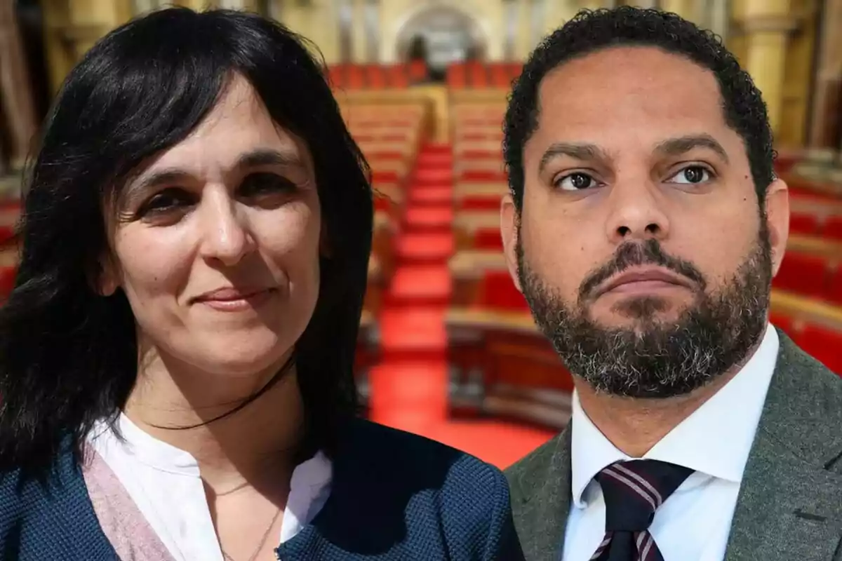 Two people pose in front of a background of red seats in what appears to be a parliamentary chamber.