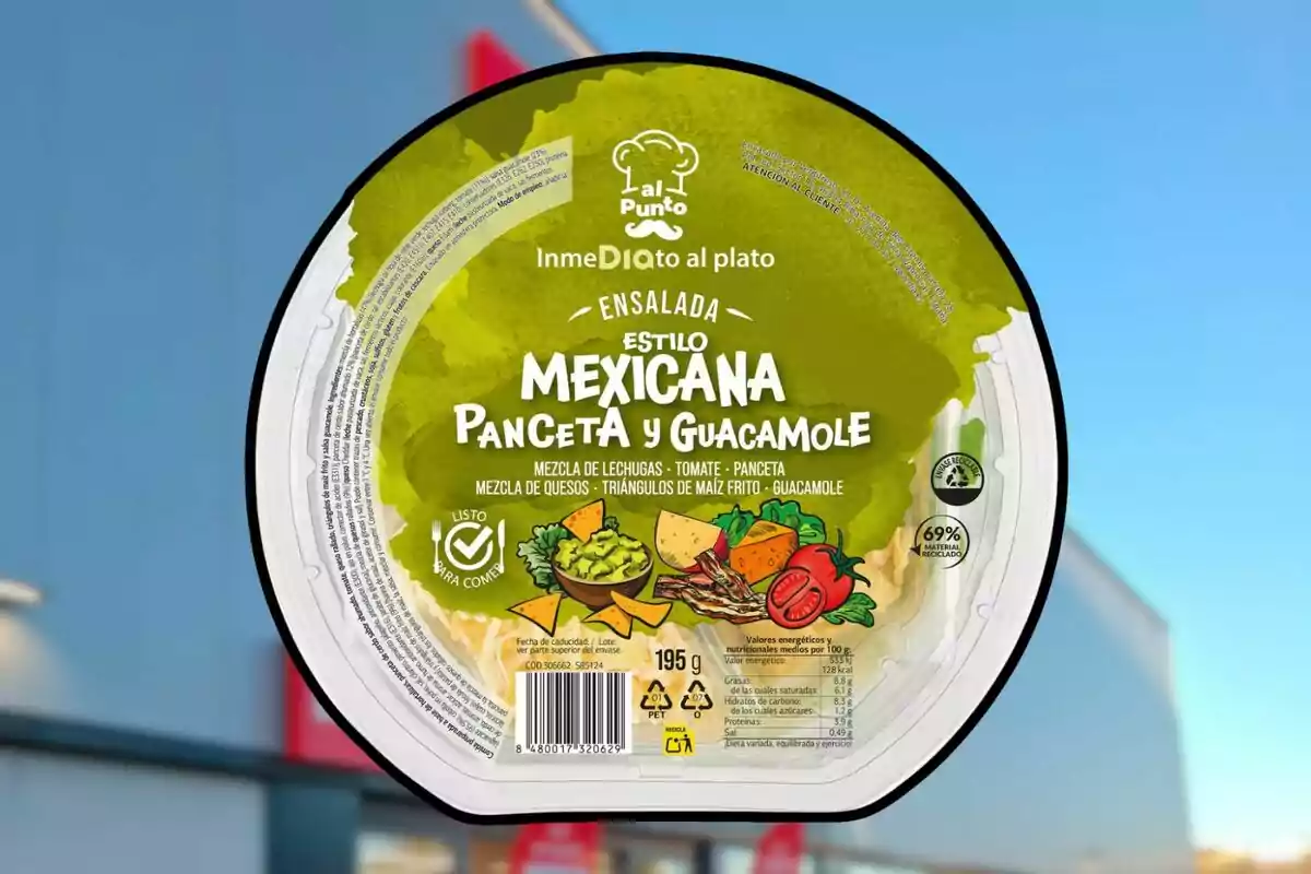Envàs d’amanida estil mexicà amb cansalada i guacamole de la marca Al Punto sostingut davant d’un fons desenfocat d’un edifici Envàs d’amanida estil mexicà amb cansalada i guacamole de la marca Al Punto sostingut davant d’un fons desenfocat d’un edifici