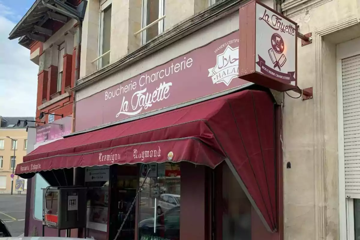 Façana d’una carnisseria i xarcuteria halal anomenada La Fayette amb tendal i rètol en tons burdeus a França. Façana d’una carnisseria i xarcuteria halal anomenada La Fayette amb tendal i rètol en tons burdeus a França.