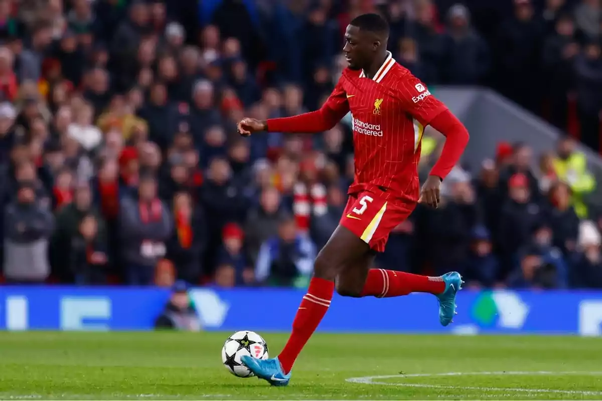 Futbolista del Liverpool amb uniforme vermell controla la pilota durant un partit en un estadi ple d’espectadors Futbolista del Liverpool amb uniforme vermell controla la pilota durant un partit en un estadi ple d’espectadors