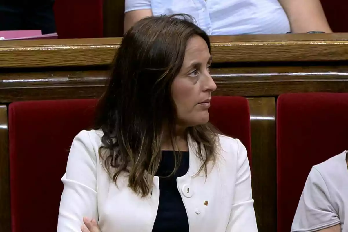 Dona de cabells castanys asseguda en un banc amb entapissat vermell mirant cap a la dreta Dona de cabells castanys asseguda en un banc amb entapissat vermell mirant cap a la dreta