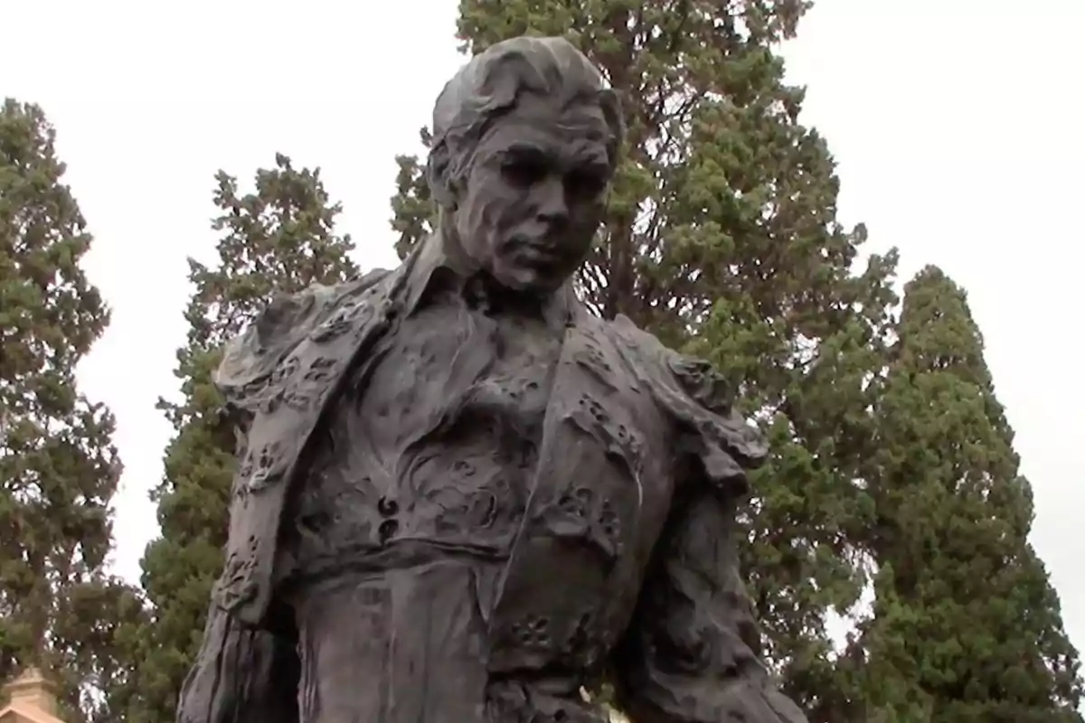 Sculpture of a bullfighter with tall trees in the background Sculpture of a bullfighter with tall trees in the background