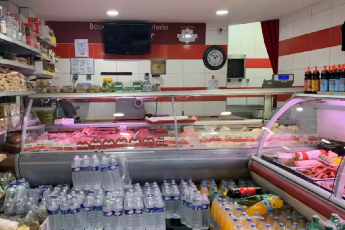 Botiga halal de queviures amb vitrines de carns fredes, ampolles d’aigua i refrescos en primer pla, prestatges amb productes i una balança al fons, situada a França. Botiga halal de queviures amb vitrines de carns fredes, ampolles d’aigua i refrescos en primer pla, prestatges amb productes i una balança al fons, situada a França.