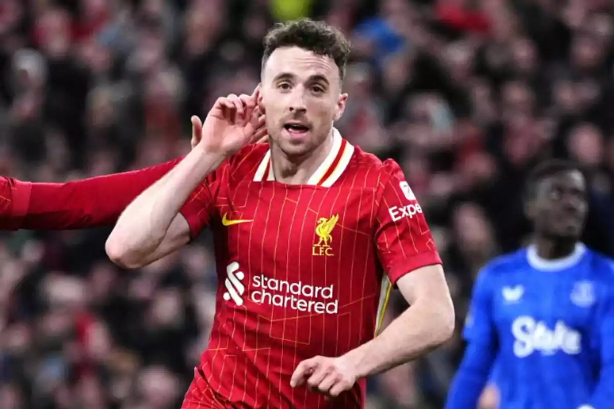 Liverpool footballer celebrating a goal in a match with his hand to his ear and a full stadium in the background Liverpool footballer celebrating a goal in a match with his hand to his ear and a full stadium in the background