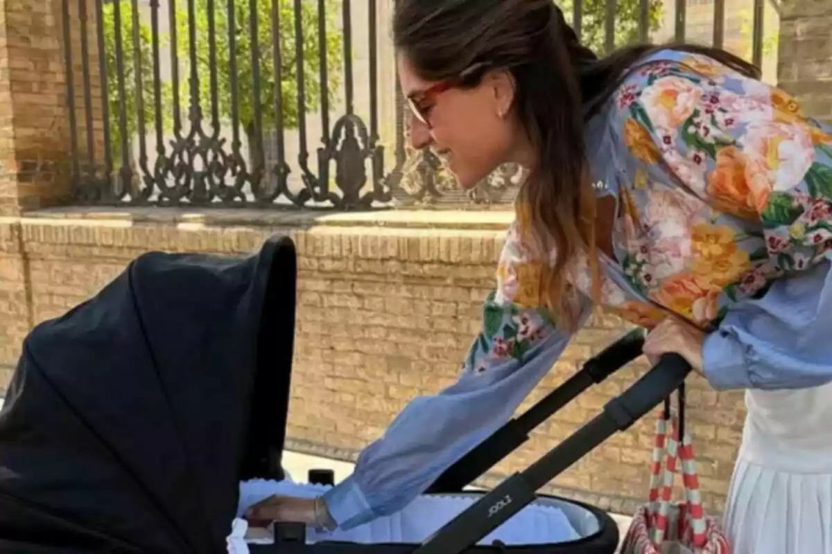 Lourdes Montes dressed in a floral blouse and sunglasses, looking at and touching a black baby stroller on the street. Lourdes Montes dressed in a floral blouse and sunglasses, looking at and touching a black baby stroller on the street.