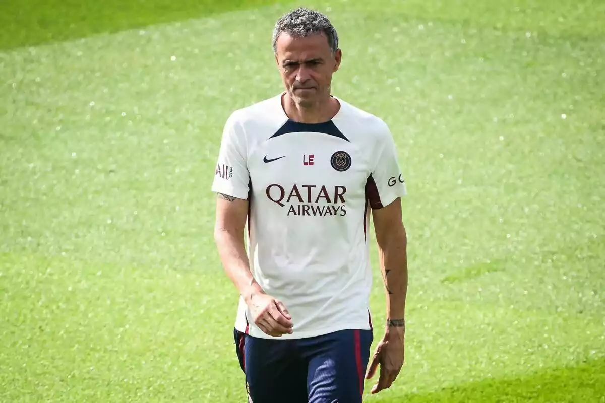 Home amb samarreta blanca del PSG caminant sobre la gespa Home amb samarreta blanca del PSG caminant sobre la gespa