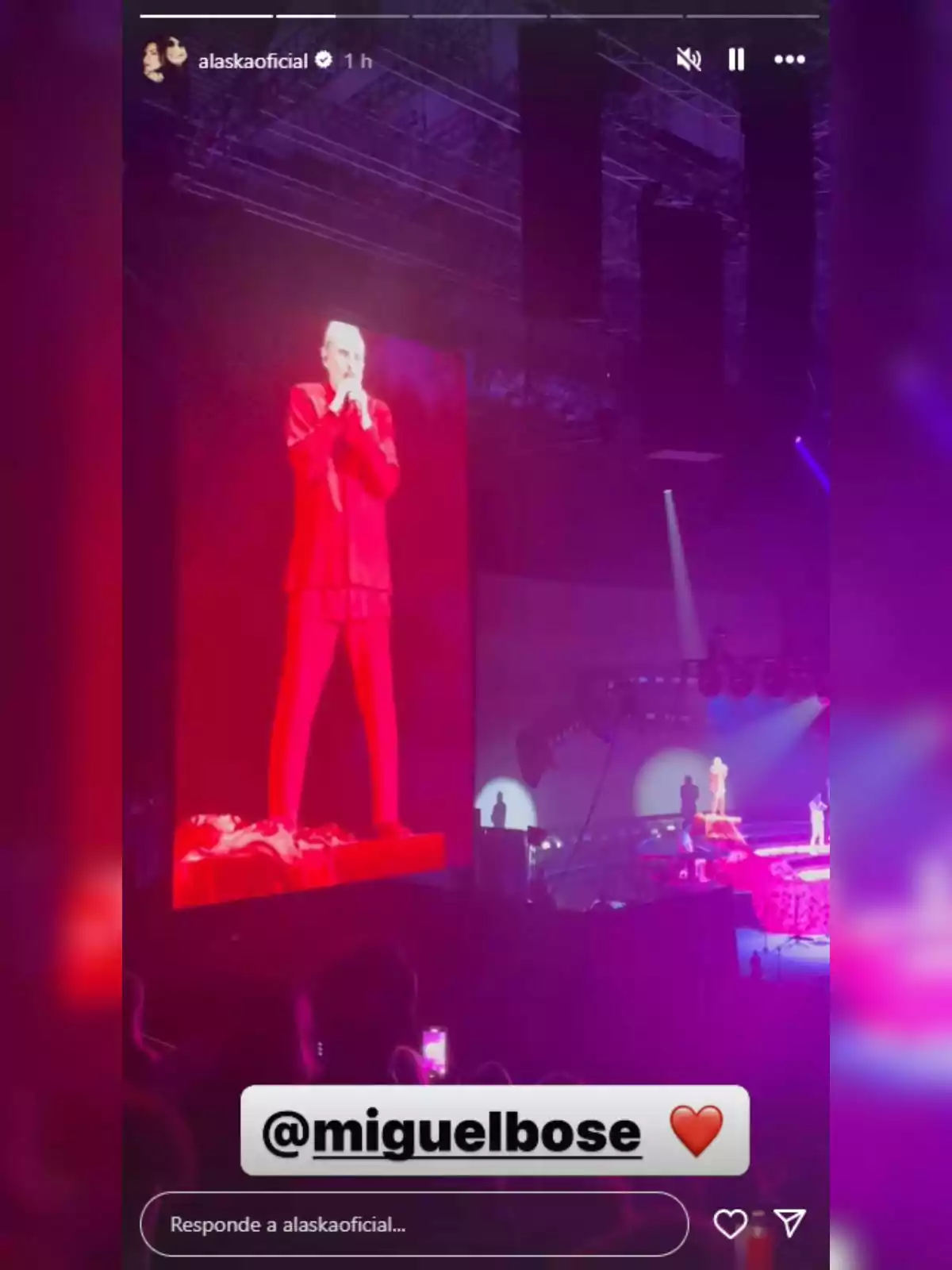 Miguel Bosé vestit de vermell es presenta en un escenari il·luminat, mentre la seva imatge apareix en una pantalla gegant i el públic observa l’espectacle. Miguel Bosé vestit de vermell es presenta en un escenari il·luminat, mentre la seva imatge apareix en una pantalla gegant i el públic observa l’espectacle.