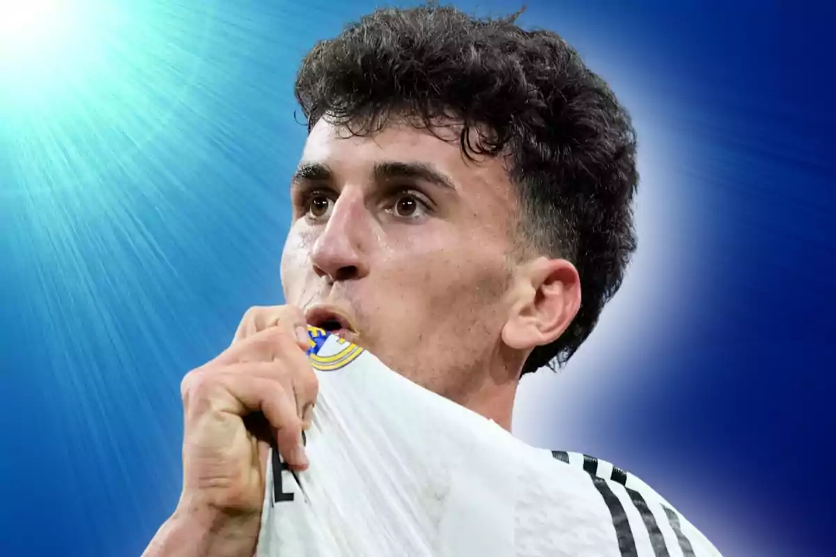 Soccer player kissing the badge on his jersey with a bright blue background