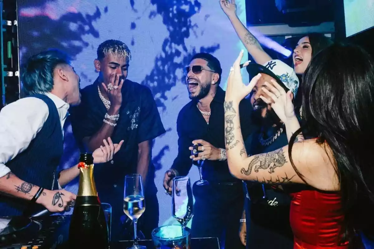 Un grup de persones joves gaudeix d’una festa en un club nocturn, rient i celebrant amb copes i ampolles sobre la taula, envoltats de llums blaves i un ambient animat. Un grup de persones joves gaudeix d’una festa en un club nocturn, rient i celebrant amb copes i ampolles sobre la taula, envoltats de llums blaves i un ambient animat.