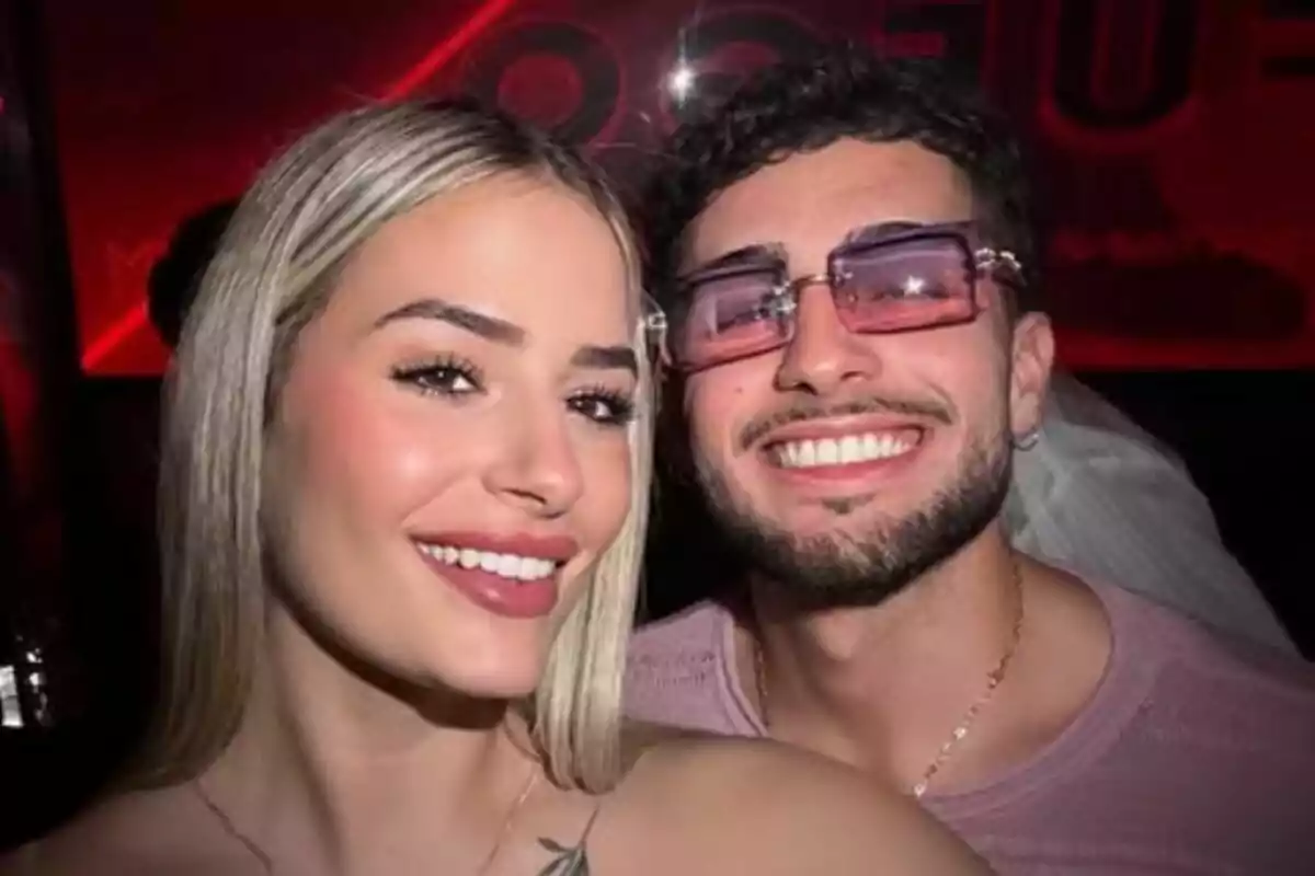 Una parella jove, formada per Laura Galera i Manu Vulcan, somriu mentre es fa una selfie en un lloc amb llums vermelles de fons. Una parella jove, formada per Laura Galera i Manu Vulcan, somriu mentre es fa una selfie en un lloc amb llums vermelles de fons.