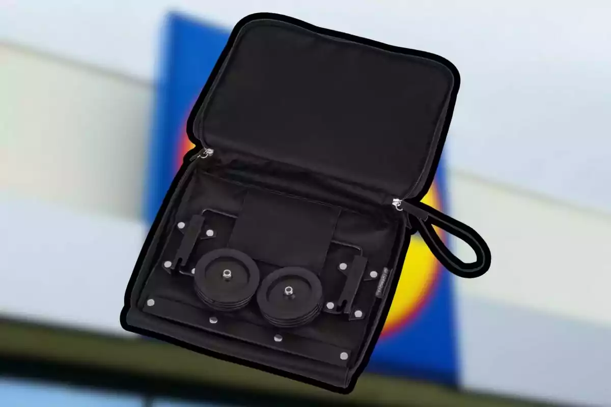 Open black briefcase containing a set of portable weights in front of a blurred background with blue, yellow, and red colors. Open black briefcase containing a set of portable weights in front of a blurred background with blue, yellow, and red colors.