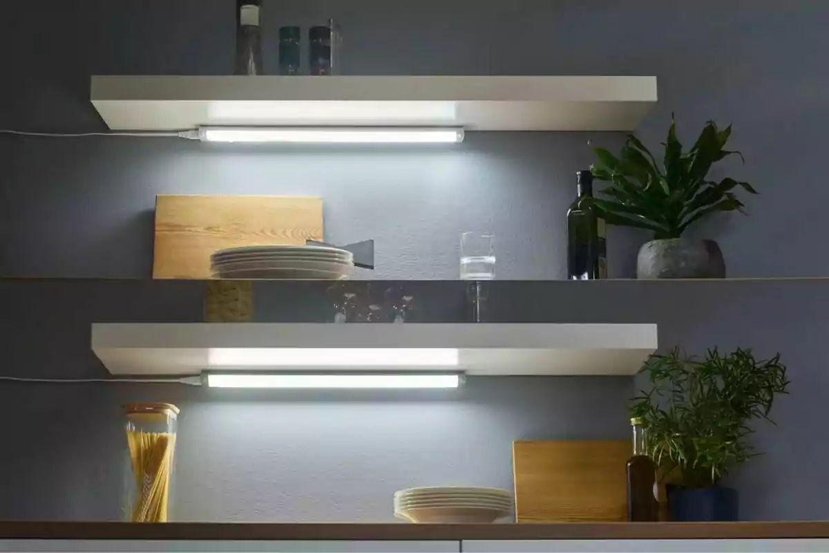 White kitchen shelves with LED lighting, plates, glasses, spice jars, bottles, plants, and wooden boards decorating a gray wall White kitchen shelves with LED lighting, plates, glasses, spice jars, bottles, plants, and wooden boards decorating a gray wall