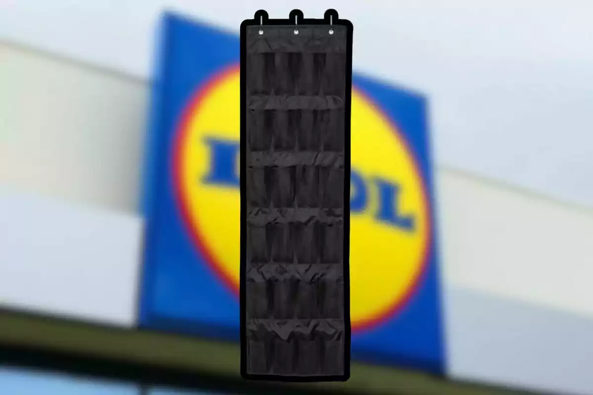 Organizador negro colgante con varios bolsillos frente a un letrero borroso de una tienda Organizador negro colgante con varios bolsillos frente a un letrero borroso de una tienda