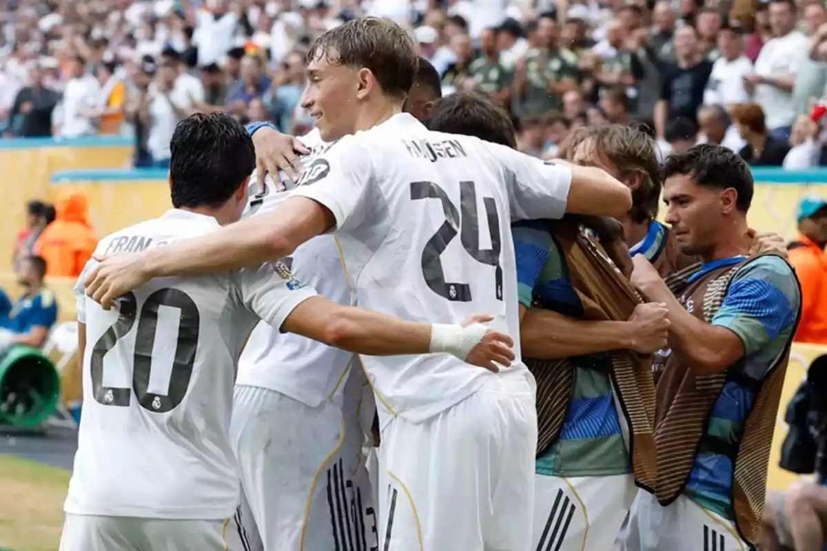 Soccer team players celebrate a goal together on the field surrounded by fans in the stands. Soccer team players celebrate a goal together on the field surrounded by fans in the stands.