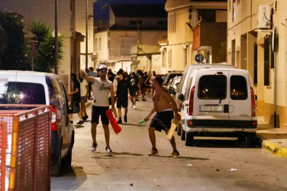 Grup de persones en un carrer durant la nit, algunes d'elles semblen estar en una situació de disturbis o enfrontament. Grup de persones en un carrer durant la nit, algunes d'elles semblen estar en una situació de disturbis o enfrontament.