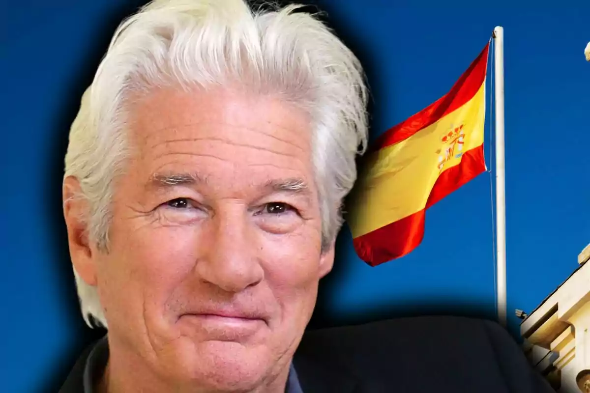 Richard Gere somrient en primer pla amb una bandera d’Espanya onejant al fons sobre un cel blau.