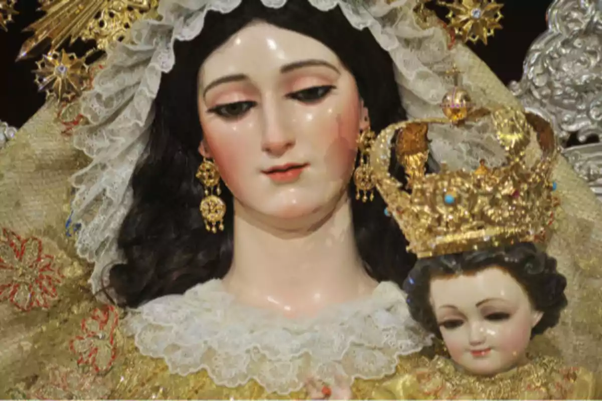 Imagen de una figura religiosa de la Virgen María con un niño en brazos ambos con coronas doradas y vestimenta decorada Imagen de una figura religiosa de la Virgen María con un niño en brazos ambos con coronas doradas y vestimenta decorada