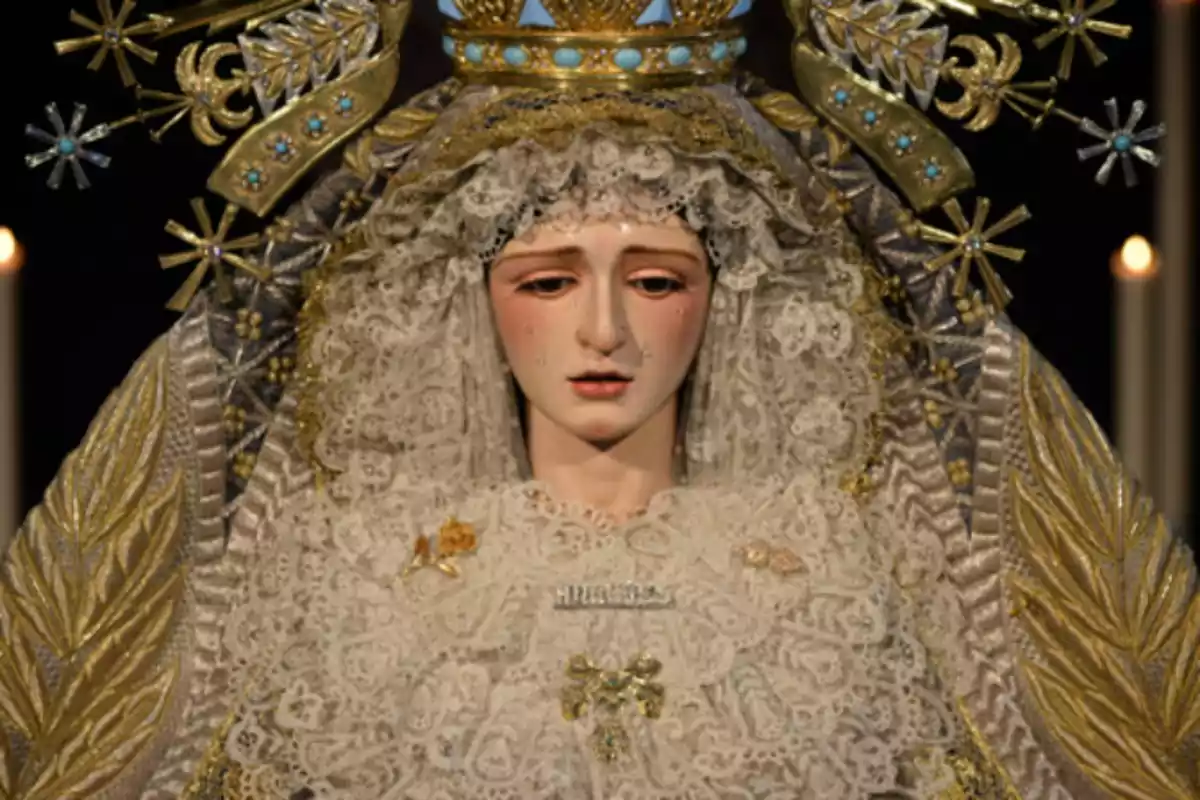 Imatge d’una figura religiosa de la Mare de Déu vestida amb mantell daurat i puntes blanques, adornada amb corona i detalls daurats Imatge d’una figura religiosa de la Mare de Déu vestida amb mantell daurat i puntes blanques, adornada amb corona i detalls daurats