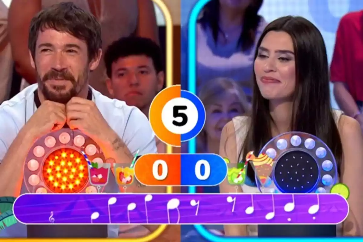 Juanjo Ballesta y Roser Tapias sonríen frente a un marcador con el número cinco en el centro y un puntaje de cero a cero en un programa de televisión de juegos. Captura de 'Pasapalabra' Juanjo Ballesta y Roser Tapias sonríen frente a un marcador con el número cinco en el centro y un puntaje de cero a cero en un programa de televisión de juegos. Captura de 'Pasapalabra'