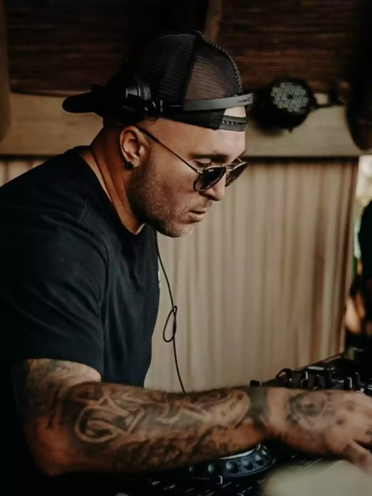 Kiko Rivera wearing a cap and sunglasses mixing music on a DJ console Kiko Rivera wearing a cap and sunglasses mixing music on a DJ console