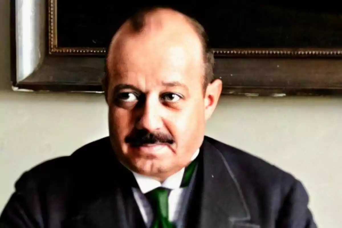 José María Quiñones de León con bigote y traje oscuro sentado frente a una pared clara y un cuadro enmarcado al fondo José María Quiñones de León con bigote y traje oscuro sentado frente a una pared clara y un cuadro enmarcado al fondo