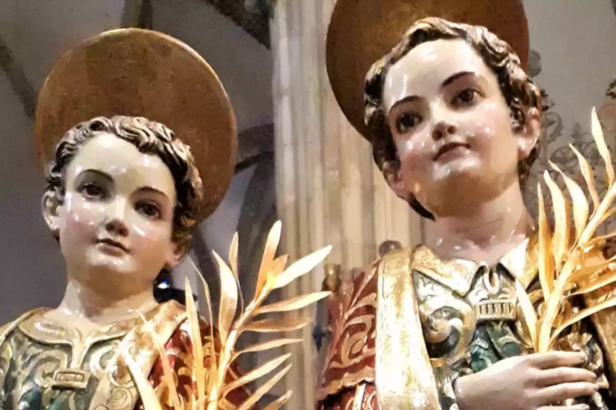 Dos esculturas religiosas de niños con aureolas doradas y vestimentas ornamentadas sosteniendo ramas doradas