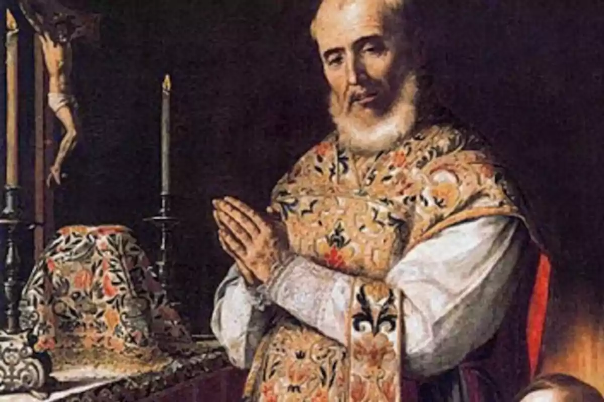 Un sacerdote de barba blanca con vestimenta ornamentada está orando frente a un altar decorado con un mantel colorido y un crucifijo