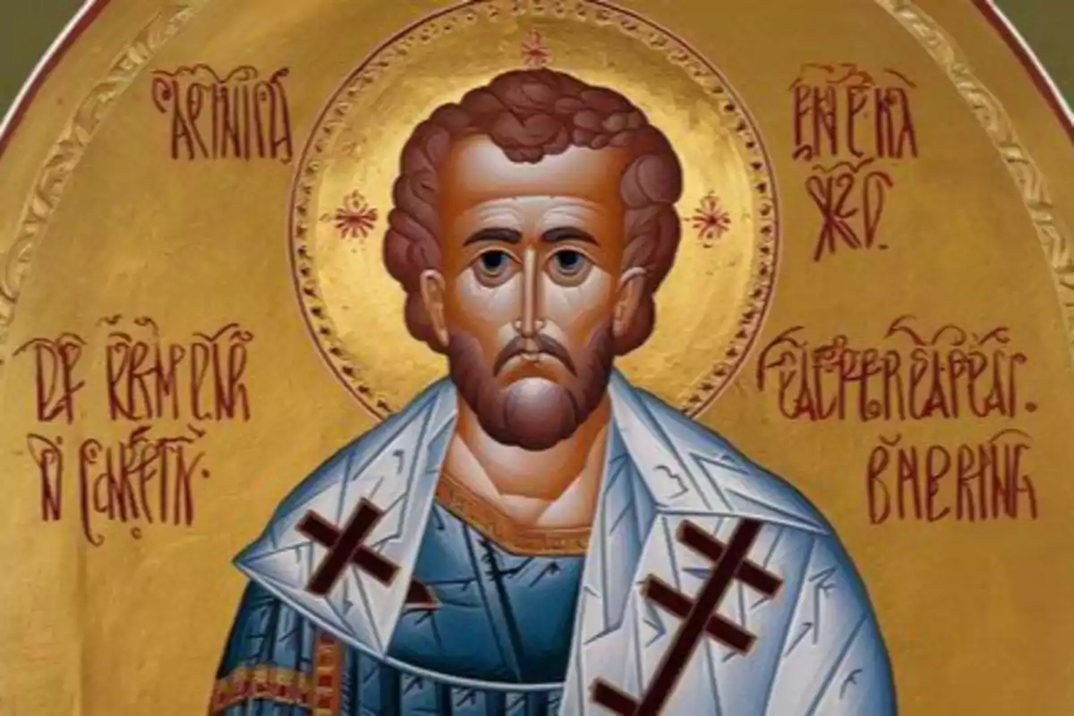 Icona religiosa d’estil bizantí que mostra un home amb barba i aurèola daurada vestit amb una túnica blava i un mantell blanc decorat amb creus negres sobre un fons daurat amb inscripcions en grec.