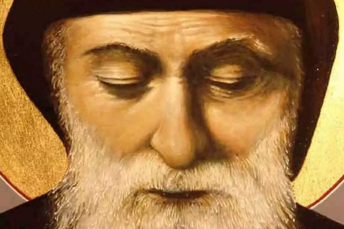 Retrat d’un home gran amb barba blanca i expressió serena, portant una caputxa fosca i un fons daurat. Retrat d’un home gran amb barba blanca i expressió serena, portant una caputxa fosca i un fons daurat.