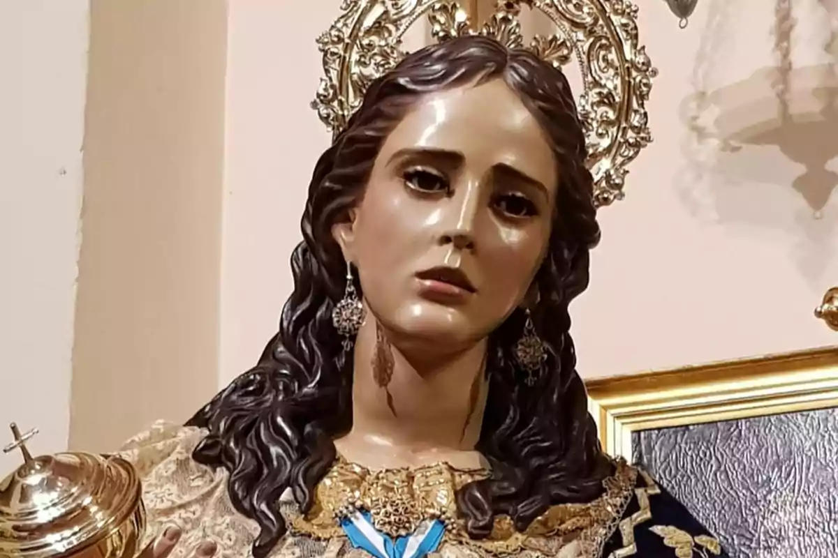 Imatge d’una escultura religiosa d’una verge amb expressió solemne, cabells foscos i arrissats, vestida amb robes decorades i una corona daurada darrere el cap