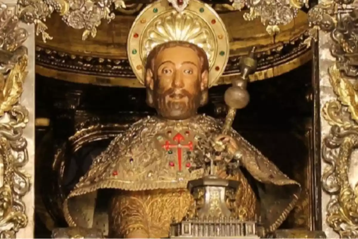 Escultura religiosa de un santo con aureola dorada y vestimenta ornamentada rodeada de detalles dorados